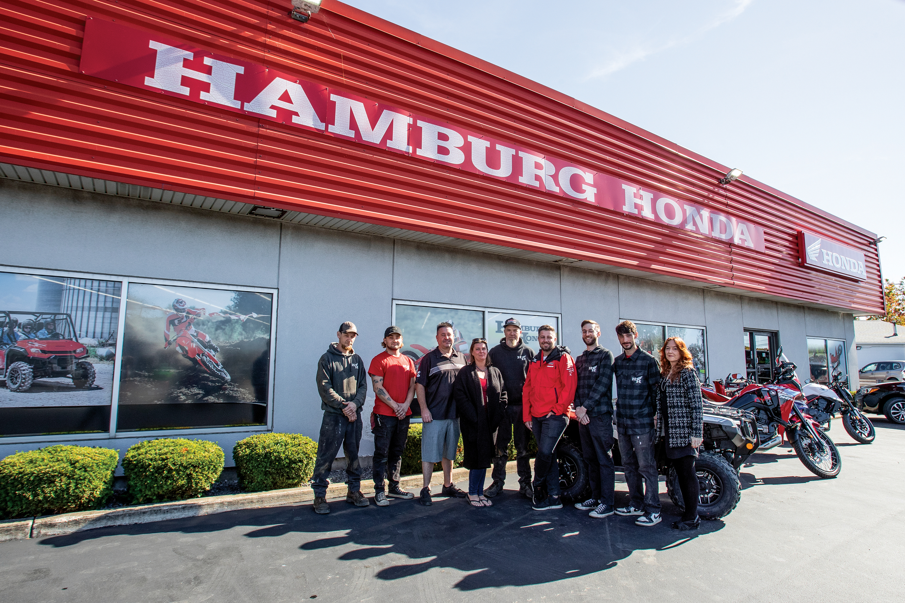 Full Hamburg Honda team standing together outside the dealership under the red Honda signage.