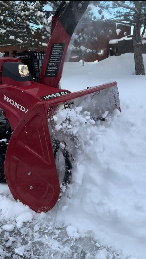 Honda HSS1332ATD track-drive snowblower throwing heavy snow during a Buffalo NY winter storm.